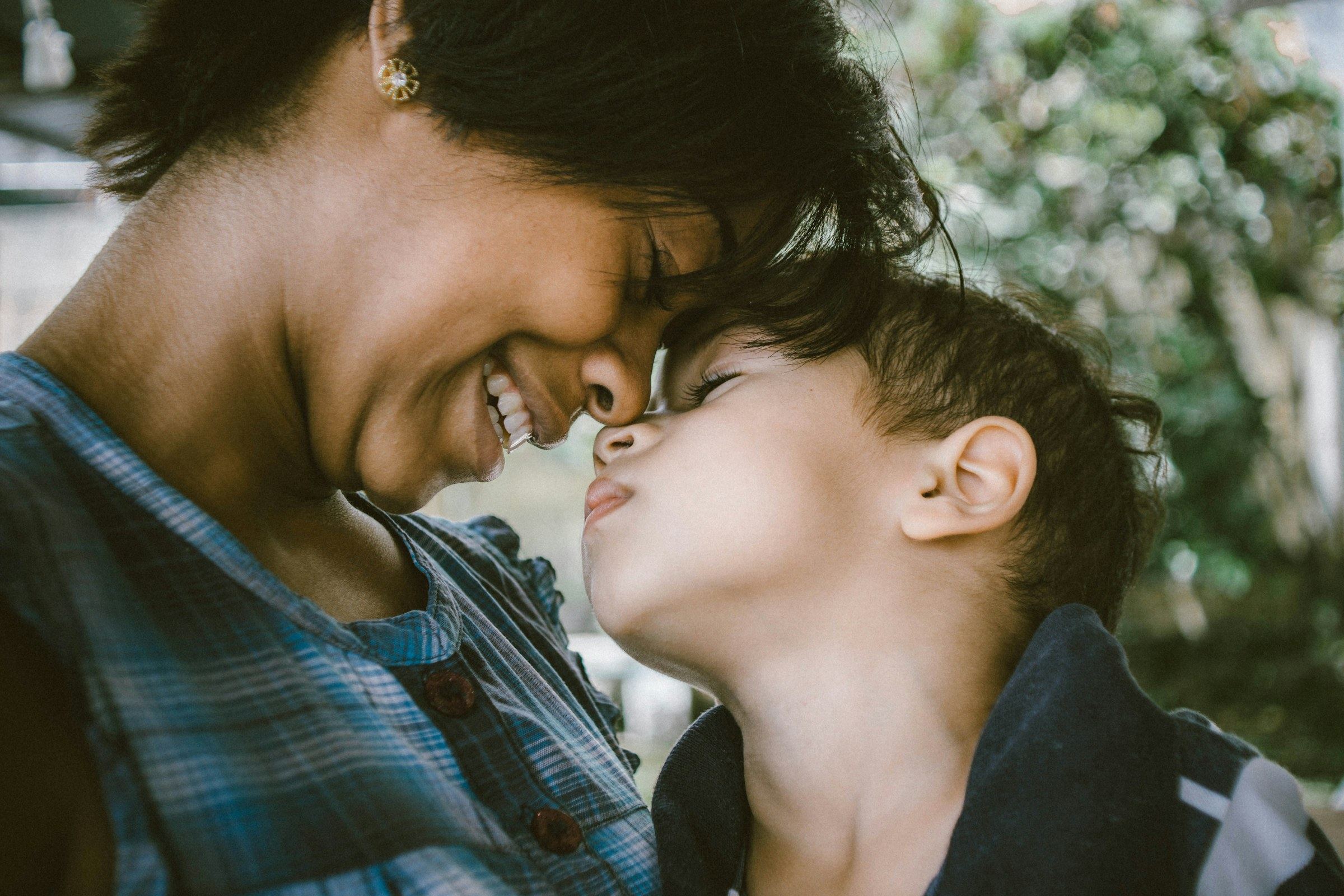 A mother and her son sharing a laugh, forehead to forehead
